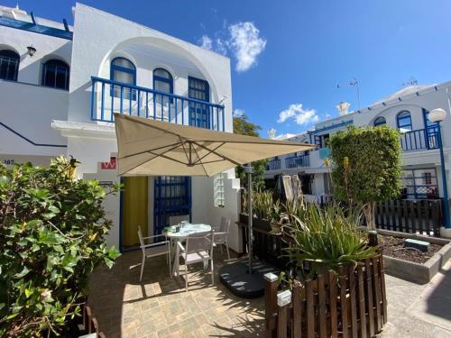 a patio with an umbrella in front of a building at PLAYMAR Refugio Palmeras in Maspalomas