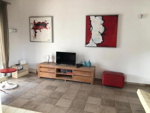 a living room with a flat screen tv and a red chair at Villa in Sisi near Beach & Olive Groves in Milatos