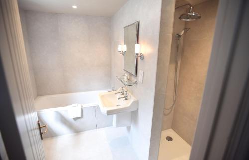 a white bathroom with a sink and a shower at The Lifeboat Inn in Hunstanton