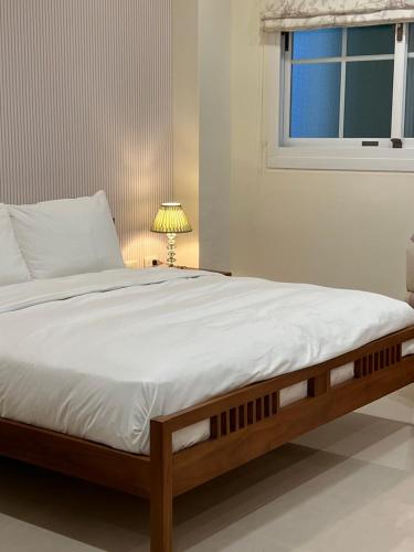 a bedroom with a bed with white sheets and a window at 屋子旅店 in Puli