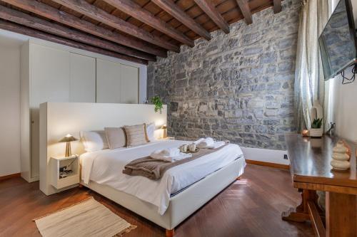 Duomo 3 Floors Penthouse في كومو: غرفة نوم بسرير ابيض وجدار من الطوب