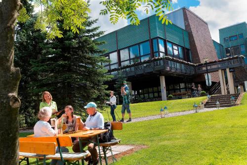 a group of people sitting at a table in front of a building at AHORN Waldhotel Altenberg in Kurort Altenberg
