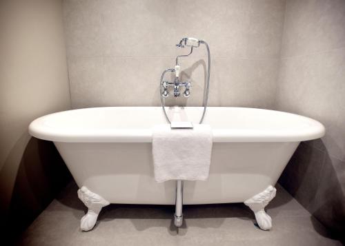 a white bath tub in a bathroom with a towel at The Lifeboat Inn in Hunstanton