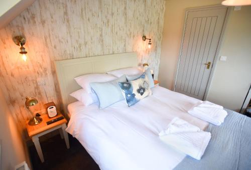 a bedroom with a white bed with blue pillows at The Lifeboat Inn in Hunstanton