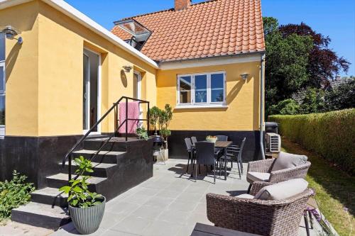 a yellow house with a patio with chairs and a table at AE316-Aeroskobing-Oster-Bregninge-45 in Ærøskøbing