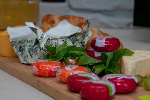 a wooden cutting board with tomatoes and cheese and bread at The Knysna Belle Guest House in Knysna