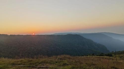a sunset in the mountains with the sun setting on the horizon at Sunset inlet homestay Cherrapunjee in Shillong