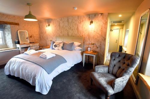 a bedroom with a large bed and a chair at The Lifeboat Inn in Hunstanton