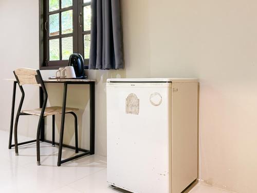 a white refrigerator next to a table and a chair at Seetanu Bungalows in Srithanu
