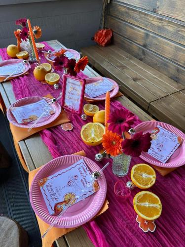 a table with pink plates and orange slices at Mazury Dom Oluś nad jeziorem Sasek Wielki z gorącą balia z funkcją jakuzzi in Szczytno