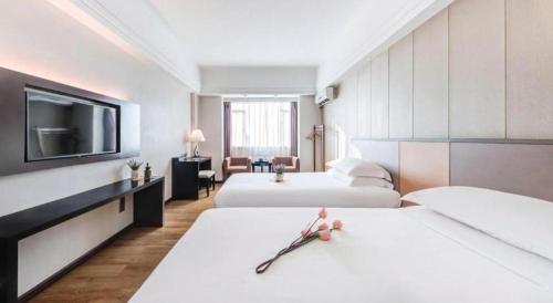 a hotel room with two beds and a flat screen tv at Zhuhai Aqueen Hotel in Zhuhai