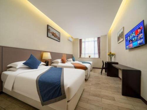 a hotel room with two beds and a flat screen tv at Zhuhai Aqueen Hotel in Zhuhai