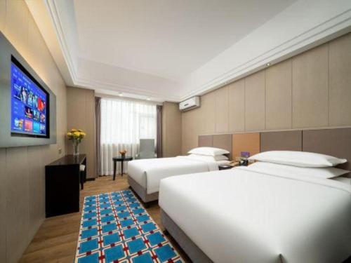 a hotel room with two beds and a flat screen tv at Zhuhai Aqueen Hotel in Zhuhai