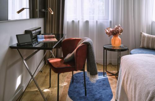 a room with a desk and a chair and a bed at The Posthouse Berlin Potsdamer Platz- Leonardo Limited Edition in Berlin