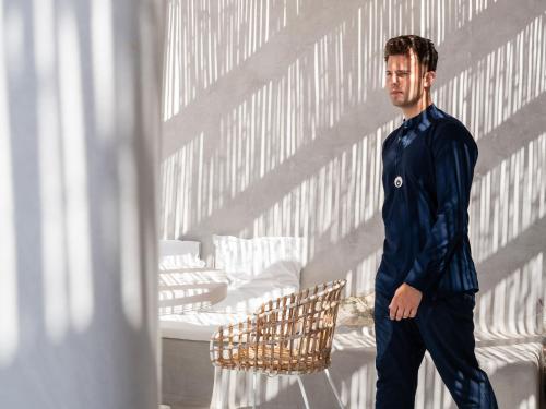 a man standing next to a chair in a room at Mykonos Blu, A Grecotel Resort to Live in Psarou