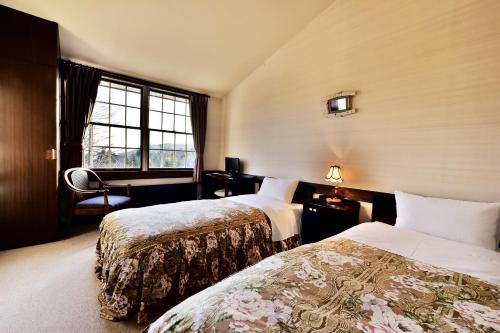 ein Hotelzimmer mit zwei Betten und einem Fenster in der Unterkunft Petit Hotel Kanan in Chino