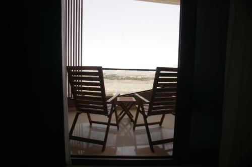 two chairs and a table in front of a window at Liaqat Airport Residence Al Mouj in Mawāliḩ