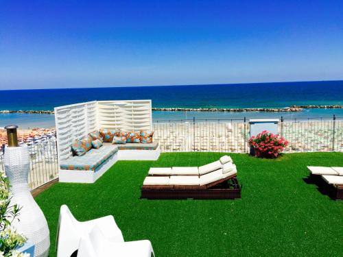 a patio with white furniture and the ocean in the background at Residence Frontemare in Rimini