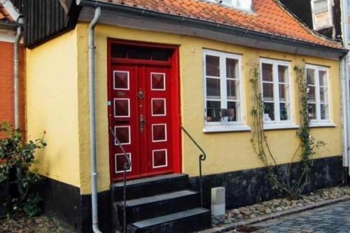 a yellow and red house with a red door at AE297-Aeroskobing-Norregade-8 in Ærøskøbing
