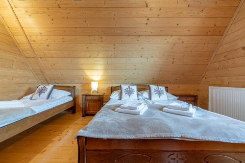 two beds in a room with wooden walls at Osada Szaflary in Szaflary