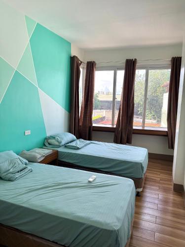 two beds in a room with blue walls and windows at Lheaf Residences and Serviced Apartments in Cebu City