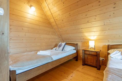 a room with two beds in a wooden cabin at Osada Szaflary in Szaflary