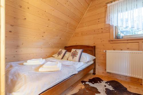 a bed in a wooden cabin with towels on it at Osada Szaflary in Szaflary