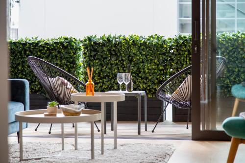 a patio with two tables and chairs and a hedge at Walk To Ponsonby and K Road Quiet Home with Blackout Blinds for the perfect sleep in Auckland