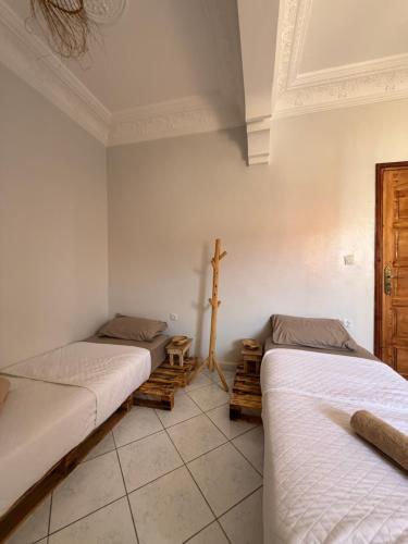 two beds in a room with white walls at Azul Berg Hostel in Tamraght Ouzdar