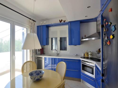 Una cocina con gabinetes azules y una mesa con sillas. en Villa in Finikounta near Sandy Beach, en Finikounta
