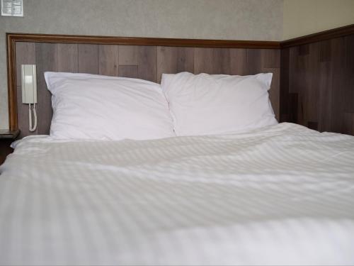 a large bed with white sheets and pillows at Tabist Centro Chita in Minamichita