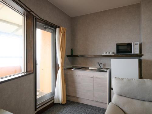 a kitchen with a window and a microwave at Tabist Centro Chita in Minamichita