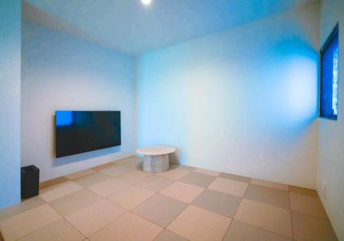 a room with a tv on the wall and a table at BEYOND THE SEA amami in Tatsugo