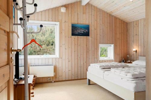 a bedroom with a bed in a room with wooden walls at TV1605-Jerup-Engblommen-3 in Jerup