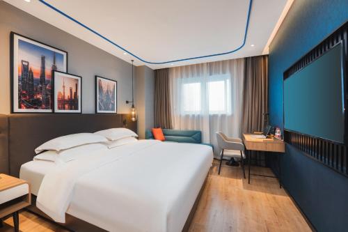 a hotel room with a large bed and a flat screen tv at Country Inn & Suite by Radisson, Shanghai Railway Station in Shanghai