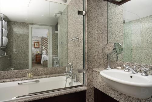 a bathroom with a sink and a tub and a mirror at The Pelham London - Starhotels Collezione in London