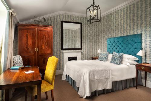 a bedroom with a bed with a blue headboard and a desk at The Pelham London - Starhotels Collezione in London