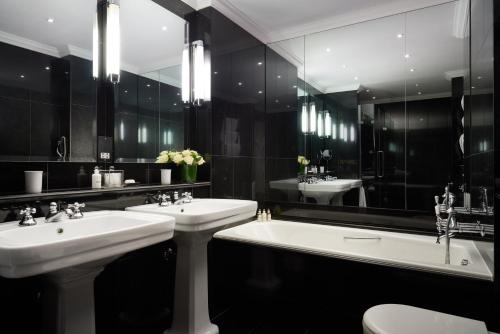 a black and white bathroom with two sinks and a tub at The Pelham London - Starhotels Collezione in London