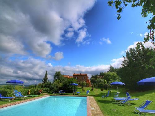 a swimming pool with blue chairs and umbrellas at Scenic Tuscan Farmhouse in San Quirico dʼOrcia