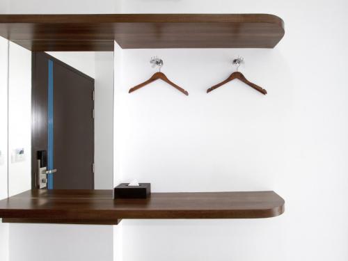 a bathroom with a mirror and a wooden shelf at Anna-Nava Pakkret Hotel in Nonthaburi