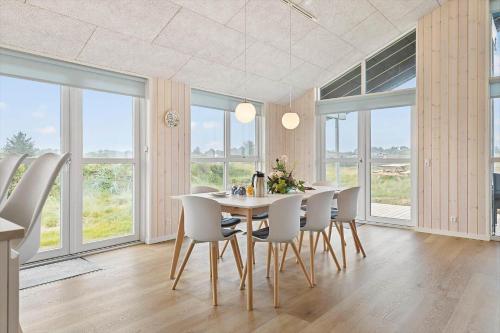 a dining room with a table and chairs and windows at TV1515-Bindslev-Paradisdalen-23-B in Bindslev