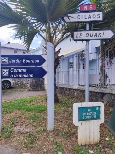 a pole with street signs in front of a palm tree at Jardin Bourbon - maison 4 étoiles - La Rivière - entre mer et montagne in Saint-Louis