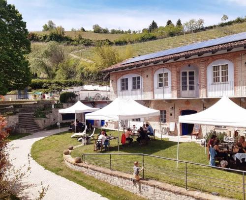a group of people sitting under umbrellas in front of a building at Cascina Il Convivio in Diano dʼAlba