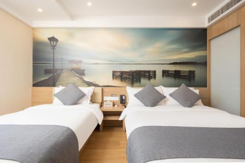 Dos camas en una habitación con un cuadro en la pared. en 智尚酒店杭州西湖湖滨浙一店, en Hangzhou