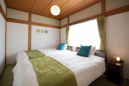 a bedroom with a large white bed with blue pillows at TUNAGU Base in Tsuruoka