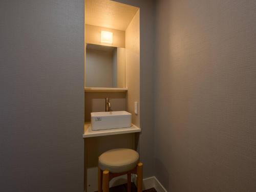 a small bathroom with a sink and a stool at Tabist Centro Chita in Minamichita