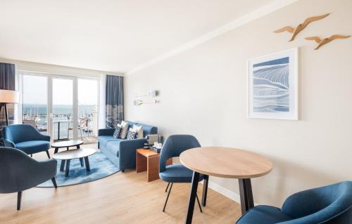 a living room with blue chairs and a table at Lindner Hotel Boltenhagen, part of JdV by Hyatt in Boltenhagen