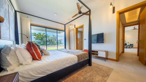 Un dormitorio con una cama grande con una ventana grande. en Pointe d'Azur Beachfront Homes - Pereybere, en Grand Baie