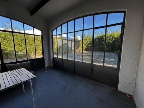 a room with windows and a table and a bench at 282 - au petit baigneur in Challans