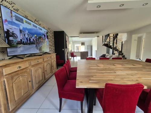 a dining room with a wooden table and red chairs at 229 - villa de la fosse a l ane in Le Fuilet